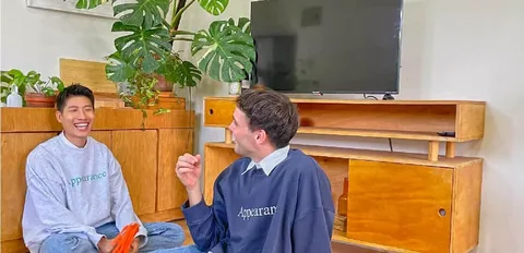 兩個人坐在改造完成的客廳地板上聊天,旁邊是植栽與木質電視櫃